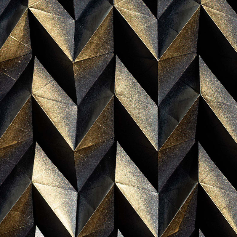 A close-up of a repeating geometric pattern of faceted diamond-like shapes in metallic gold and dark charcoal gray.