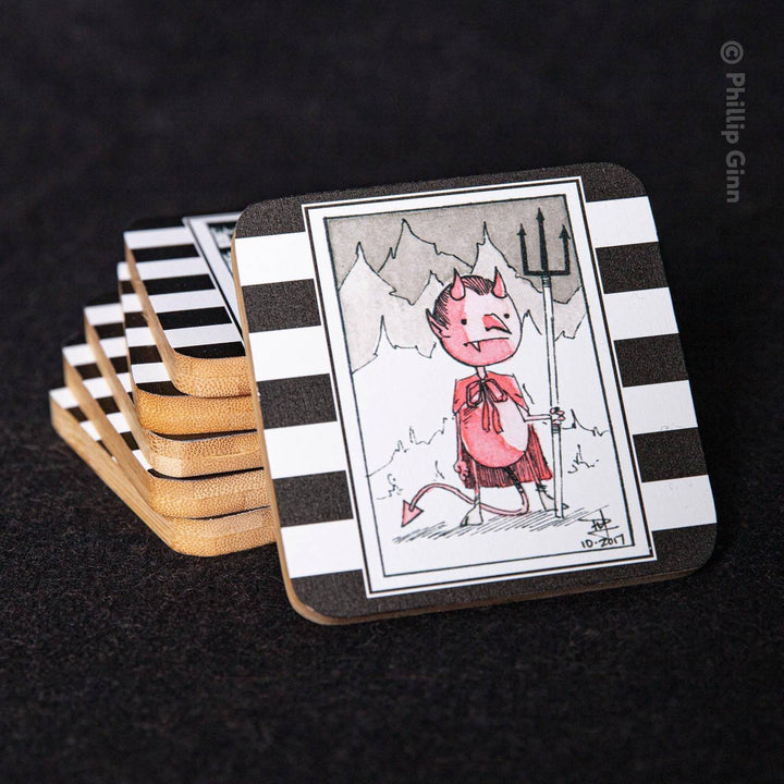 A stack of square coasters with black and white horizontal stripes, featuring a central illustration of a pink devil character holding a pitchfork against a mountain background. The front coaster is shown upright on a dark textured surface, with the remaining coasters fanned out behind it.