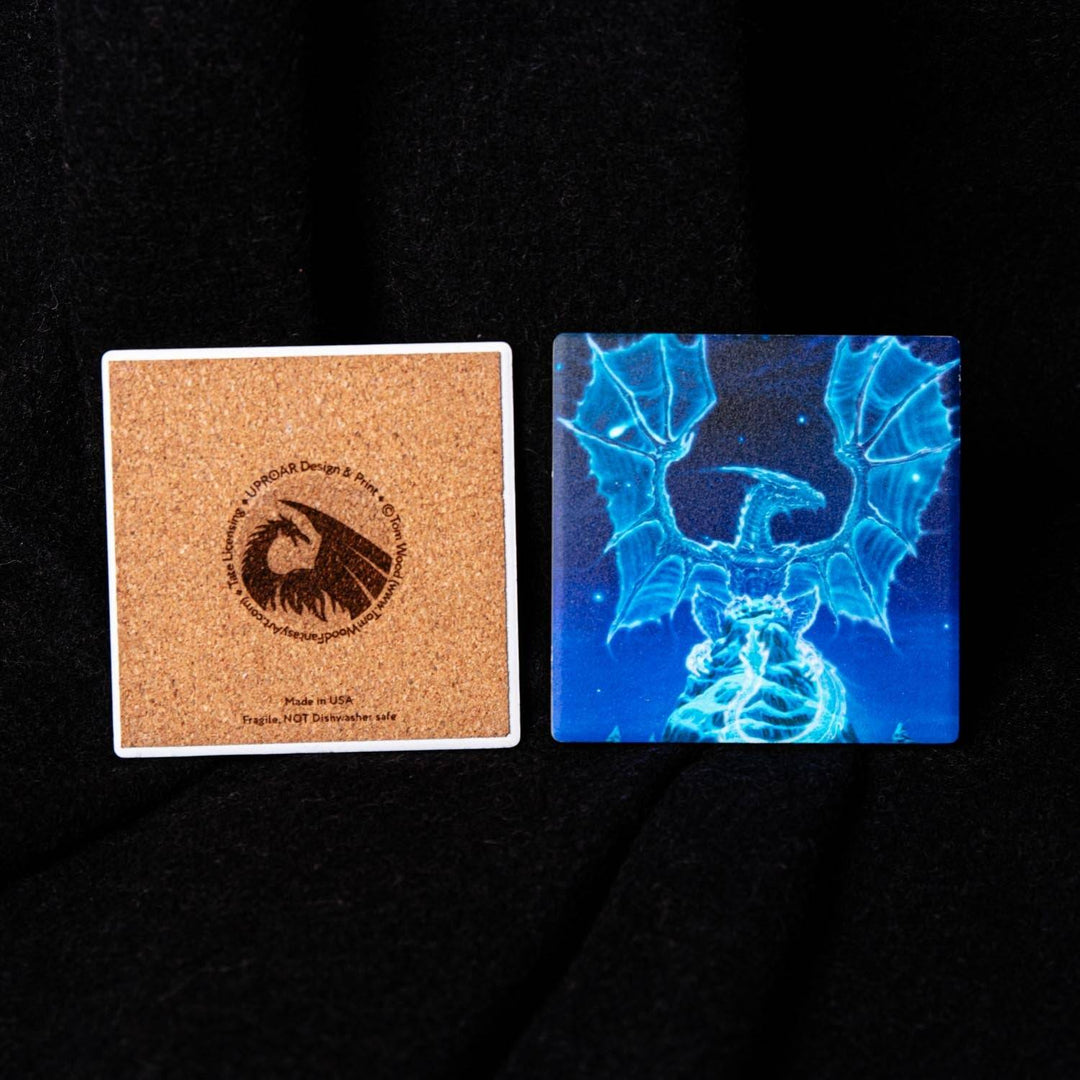 Two square coasters displayed side-by-side on a black fabric background. The coaster on the left is made of natural cork with a printed circular eagle logo and text.