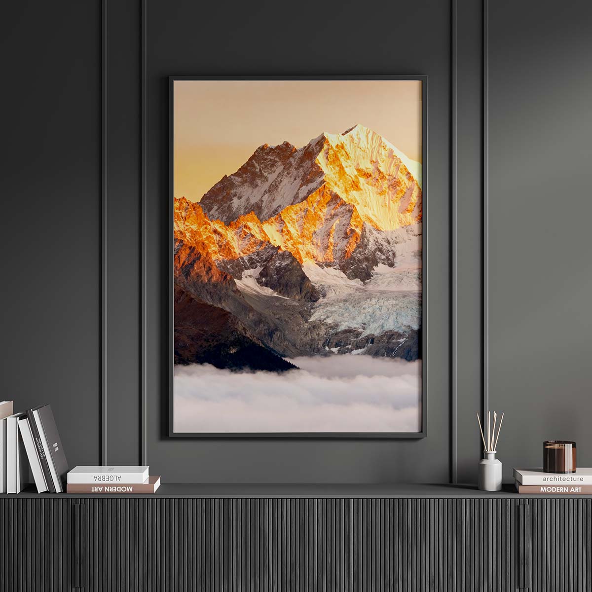 Framed mountain landscape print on a dark wall with decorative items below.