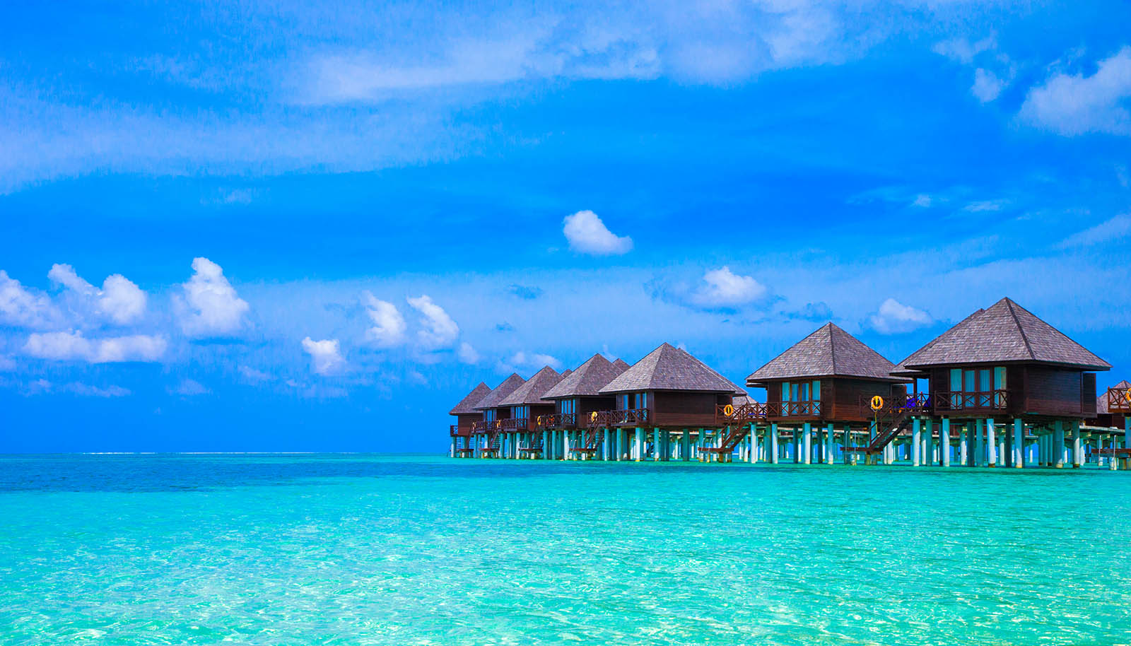 Overwater bungalows with a clear blue sky and turquoise water