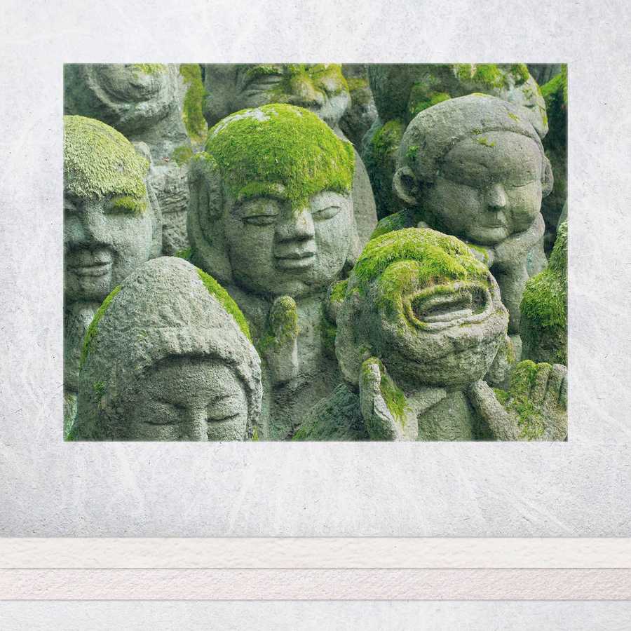 Moss-covered stone statues with various expressions on a textured white background
